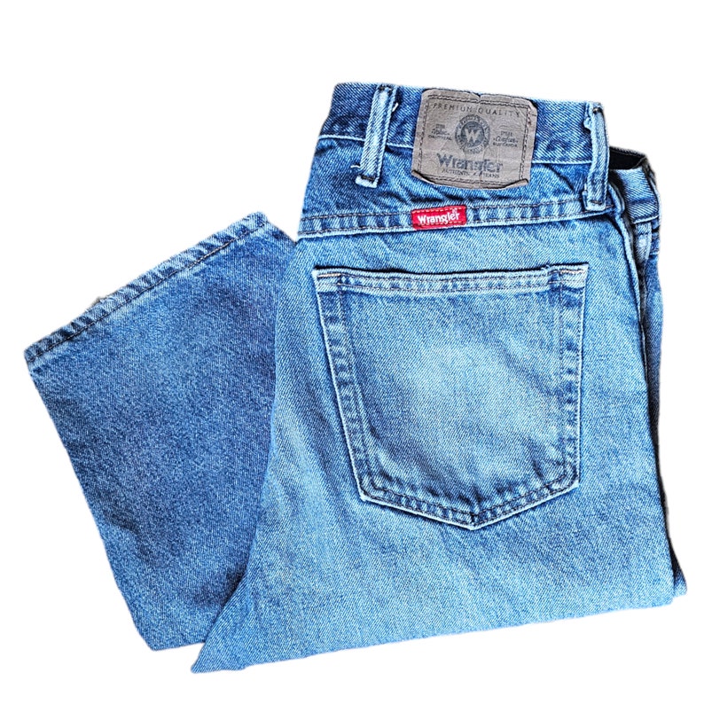 May include: A pair of blue denim jeans with a brown leather patch that says "Premium Quality Wrangler" and a red patch that says "Wrangler".