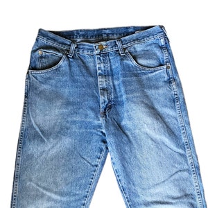 May include: A pair of blue denim jeans with a button fly and five pockets.