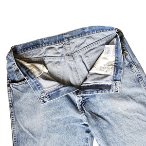 May include: A pair of light blue denim jeans with a button fly and a zipper. The jeans are turned inside out, showing the waistband and the inside of the pockets.