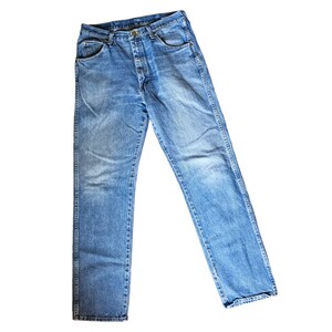 May include: A pair of blue denim jeans with a button fly and five pockets.