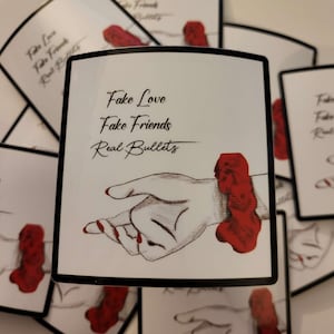 May include: White square with black border featuring the text "Fake Love, Fake Friends, Real Bullets" above a hand illustration. The hand is holding a red shape. Multiple similar squares are in the background.