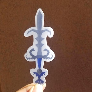 May include: A blue and gray sword sticker with a detailed design. The sticker is on a brown background.