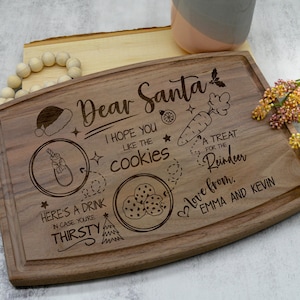 May include: A wooden cutting board with a Christmas-themed design. It says "Dear Santa, I hope you like the cookies. A treat for the reindeer. Love from Emma and Kevin."