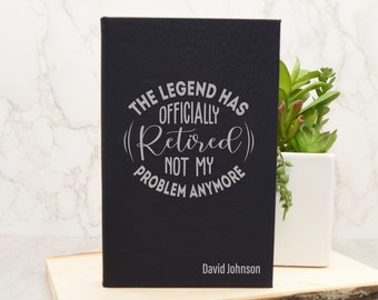 May include: Black leather journal with the text "The Legend Has Officially (Retired) Not My Problem Anymore" and the name "David Johnson" in silver lettering.