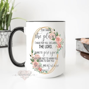 May include: White ceramic mug with a black handle and rim, featuring the text "For I know the plans I have for you, declares the Lord" surrounded by a floral design. The mug also has the text "Jeremiah 29:11".