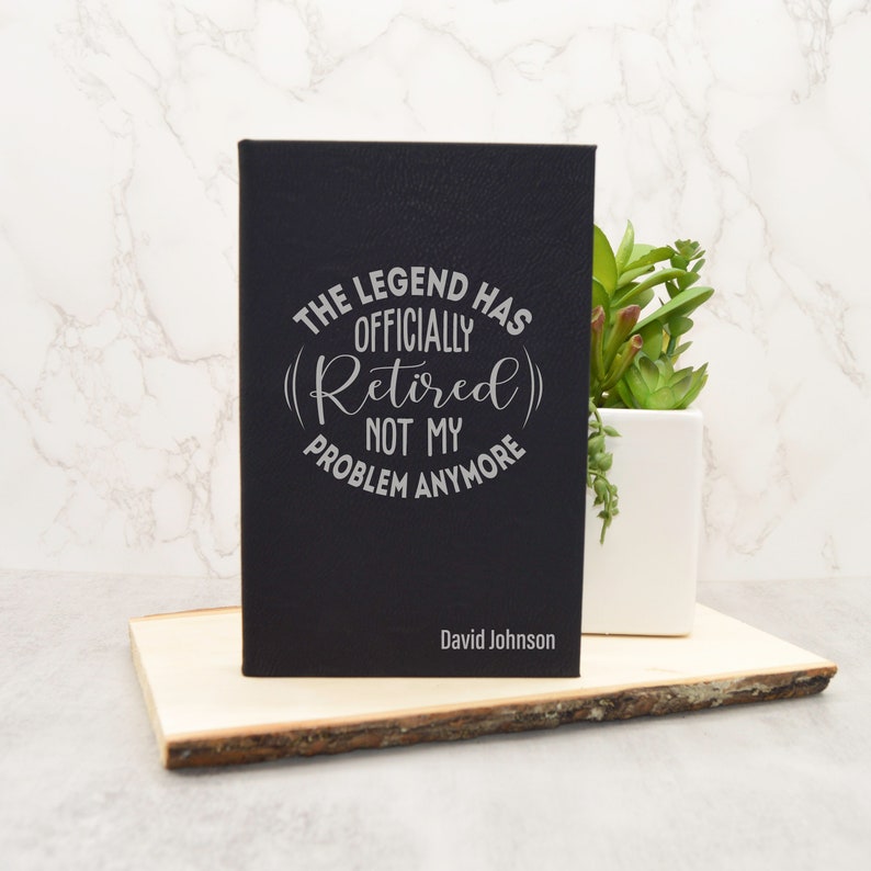 May include: Black leather journal with the text "The Legend Has Officially (Retired) Not My Problem Anymore" and the name "David Johnson" engraved on the front.