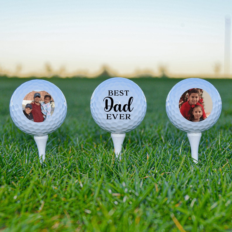 May include: Three white golf balls with personalized photos and text. The middle ball has the text "BEST Dad EVER".