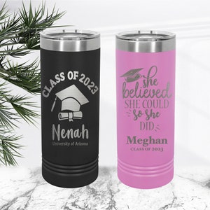 May include: Two stainless steel tumblers with personalised graduation designs. The black tumbler features a graduation cap and diploma with the text "Class of 2023" and the name "Nenah" along with the text "University of Arizona". The pink tumbler features a graduation cap and the text "She believed she could so she did" and the name "Meghan" along with the text "Class of 2023".