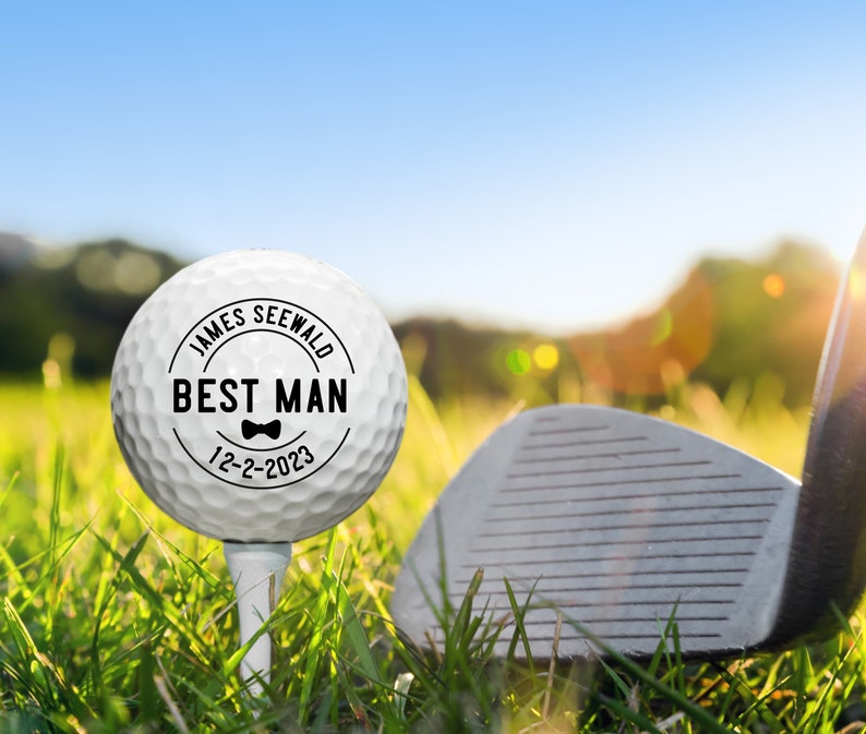 May include: White golf ball with a black circle and the text "JAMES SEEWALD BEST MAN 12-2-2023" with a bow tie graphic.