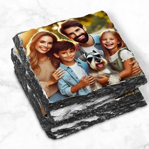 May include: A family of four, including a dog, pose for a photo in a natural setting. The photo is printed on a set of black slate coasters.