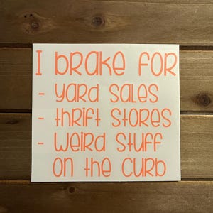 May include: White sticker with orange text that reads "I brake for - yard sales - thrift stores - weird stuff on the curb."