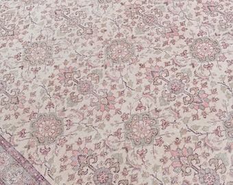 May include: A large, rectangular rug with an intricate floral pattern. The rug features a cream-colored background with repeating floral motifs in shades of pink, green, and brown. A border in a darker shade of pink frames the rug.