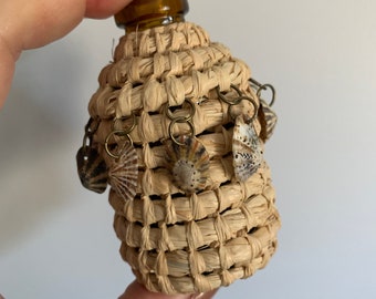 Handmade aboriginal weaving covered vintage bottle with limpet shells