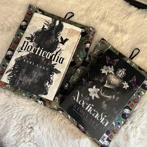 Op de afbeelding: Twee groene boekomslagen met een zwart-witte illustratie van een schedel en bloemen. De omslagen zijn voorzien van de titel "Nocticadia" en de auteur "Keri Lake".