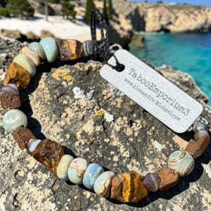 May include: A handmade wooden sign with the text "Welcome" in a playful font. The sign is painted white with a distressed finish, and features a decorative floral design in shades of pink and green. It measures approximately 12 inches wide.