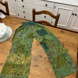May include: Green patchwork pants with a floral pattern. The pants have a wide leg and a comfortable elastic waistband.