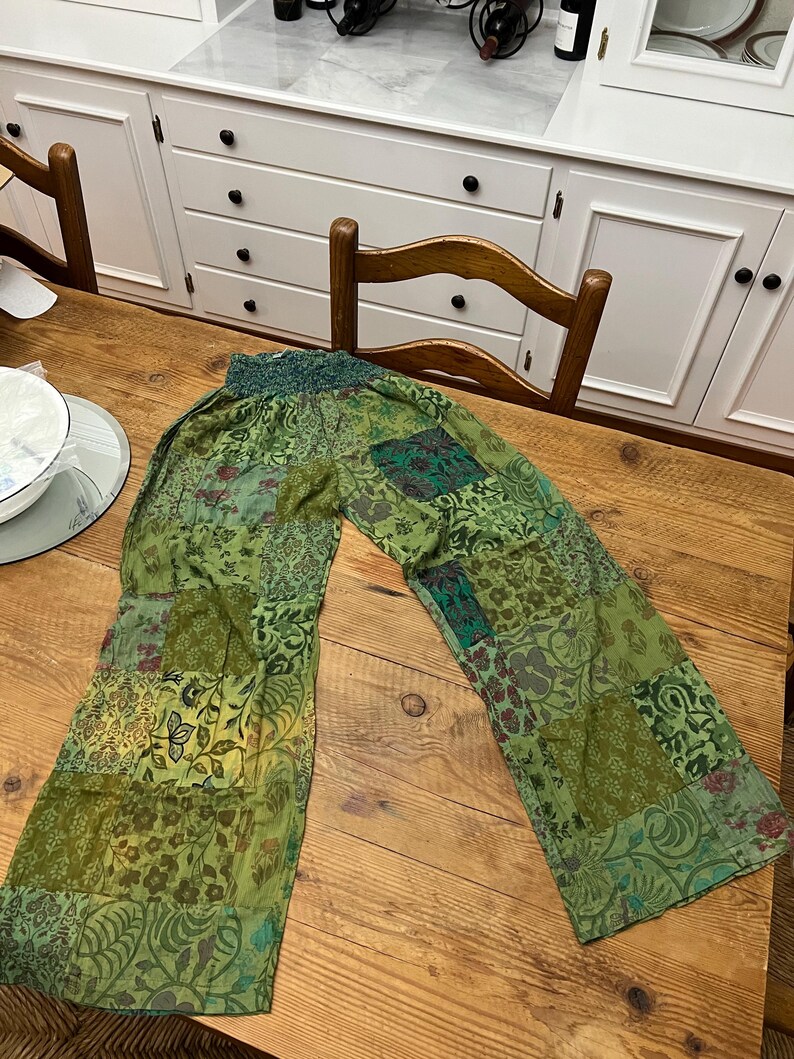 May include: Green patchwork pants with a floral pattern. The pants have a wide leg and a comfortable elastic waistband.