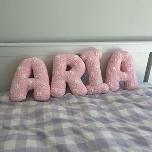 Almohada con letra y flor rosa