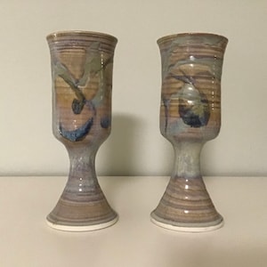 May include: Two ceramic goblets with a brown, white, and blue glaze. The goblets have a swirling design and a wide base.