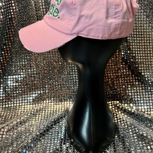 Puede incluir: Gorra de b&eacute;isbol rosa con una frase bordada en verde "Totally Basic" en la parte delantera.