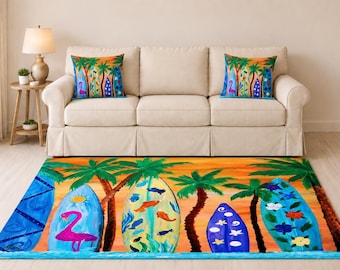 Puede incluir: Una alfombra rectangular y dos cojines a juego con una vibrante escena tropical que incluye cielos de atardecer naranja, palmeras verdes y tablas de surf azules decoradas con flamencos rosas, peces naranjas y motivos florales.