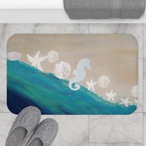 May include: A rectangular bath mat featuring a beach scene with a blue wave, sand, and white starfish, sand dollars, and a seahorse. The mat is beige and blue with a rounded edge. Gray slippers are at the bottom.