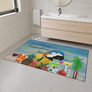 May include: A rectangular bath mat with a tropical theme. It features a colorful parrot, cocktails, and the text "It's 5 O'Clock Somewhere" against a blue and white background. The mat is placed on a tiled floor.
