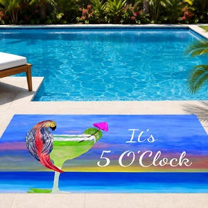 May include: A rectangular floor mat featuring a colorful illustration of a parrot perched on a green margarita glass with a pink umbrella. The background depicts a sunset over a blue ocean, with the white text "It's 5 O'Clock" printed on the right.