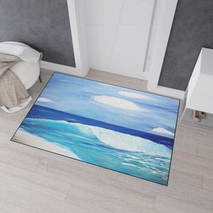 Könnte beinhalten: Eine rechteckige Fußmatte mit einem Ozeanwellen-Design. Das Kunstwerk zeigt einen blauen Himmel mit weißen Wolken über einer türkisfarbenen Welle. Die Welle bricht sich mit weißem Schaum und einem dunkelblauen Ozean.