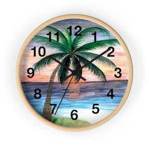 May include: A round wall clock with a light wood frame. The clock face features a watercolor painting of a palm tree on a beach at sunset. The clock hands are black, and the numbers are in a black, simple font.