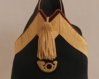May include: A black felt hat with gold trim and a gold tassel. The hat has a gold horn emblem on the front.