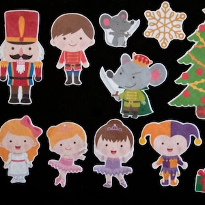 May include: A set of 11 colourful felt Christmas-themed cutouts. The cutouts include a nutcracker, a Christmas tree, a snowflake, a ballerina, a jester, a mouse, and a gift box.