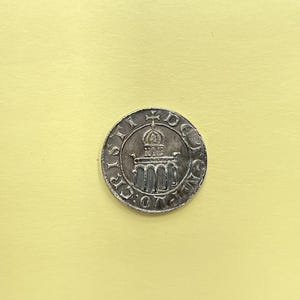 Op de afbeelding: Een zilveren munt met een gebouw en de tekst "S.P.Q.R." rond de rand.