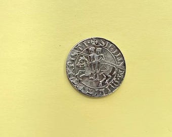 May include: A silver coin with a design of three knights on horseback, surrounded by a circular inscription in Latin. The inscription reads "SIGILLVM CIVITATIS LVGDVNI".