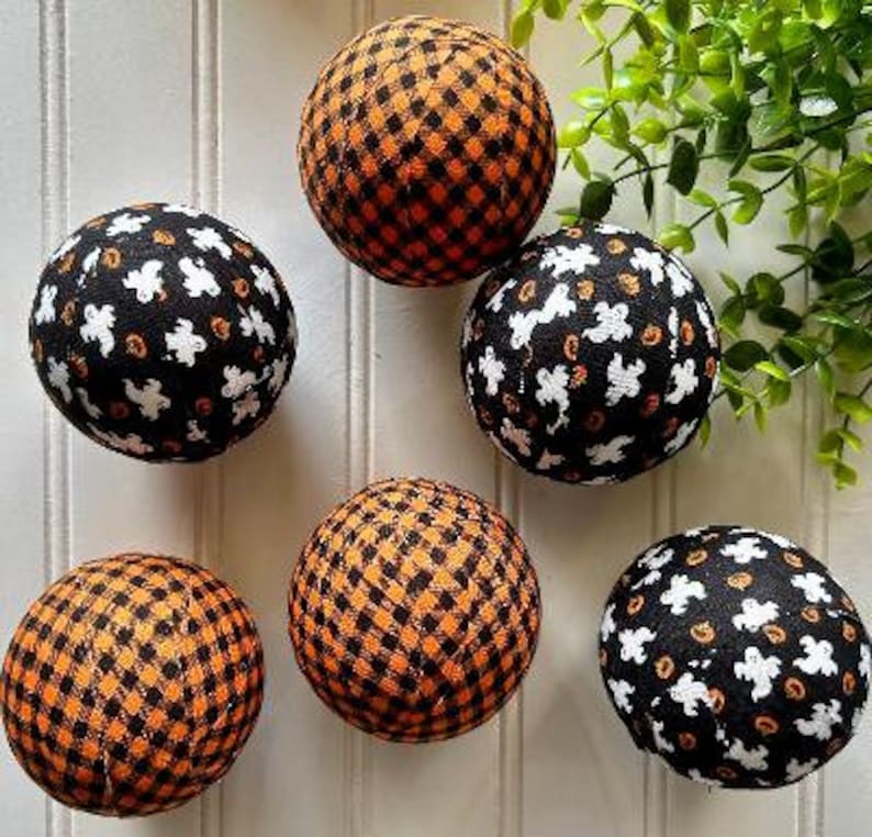 May include: Six Halloween-themed fabric balls with different patterns.  The balls are black and orange with white ghost and pumpkin designs.