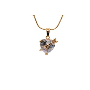 May include: A gold chain necklace with a heart-shaped pendant featuring a clear crystal and an arrow piercing through it.