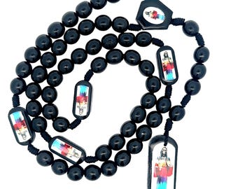 May include: Black rosary beads with colorful images of a religious figure. The beads are strung on a black cord and have a large pendant with a similar image.