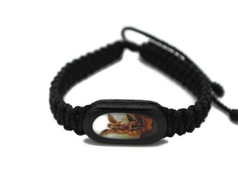 May include: Black braided bracelet with a wooden oval charm featuring a colorful image of an angel.