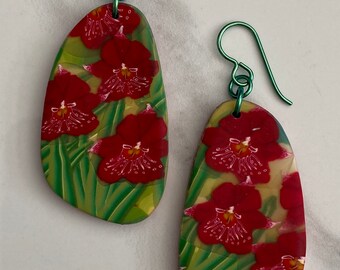 Pendientes de orquídea roja con hojas verdes