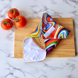 Retro rainbow sandwich wrap on a wooden bread board.  WHite hook and loop tape securely closes the sandwich inside.