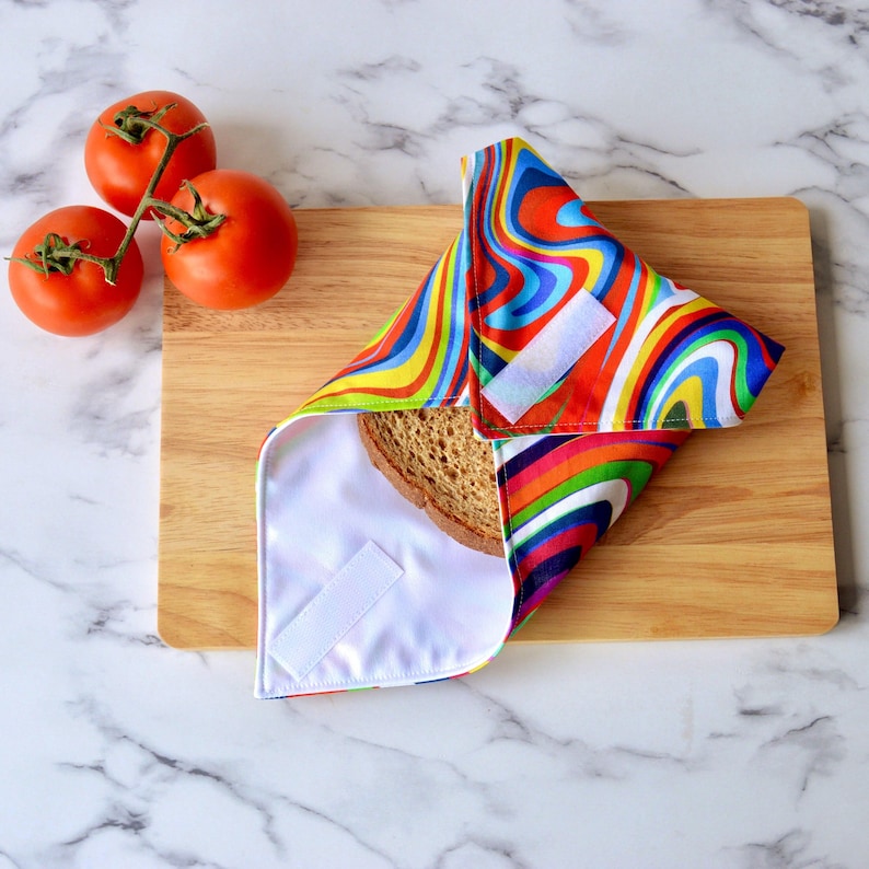 Retro rainbow sandwich wrap on a wooden bread board.  WHite hook and loop tape securely closes the sandwich inside.