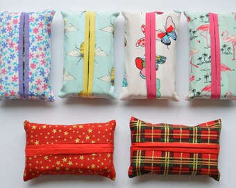 Puede incluir: Seis fundas rectangulares de tela para pañuelos con varios estampados, incluyendo flores, abejas, mariposas, flamencos, estrellas y cuadros. Cada funda tiene una abertura central con un borde de tela en contraste.