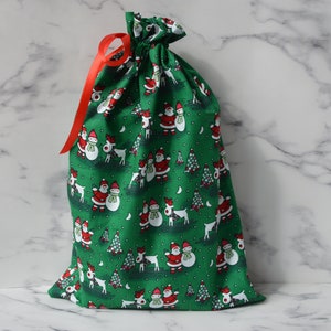 May include: Green fabric gift bag with a drawstring closure and a red ribbon. The bag is decorated with a repeating pattern of snowmen, reindeer, and Christmas trees.