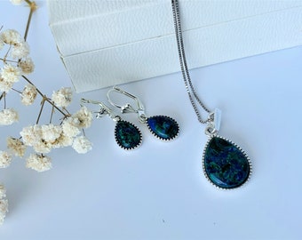 May include: A silver necklace and earrings set with teardrop-shaped green and blue gemstone pendants.