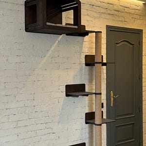 May include: A wall-mounted cat tree with a house, a scratching post, and multiple platforms. The cat tree is made of dark wood and has a natural rope scratching post. The cat tree is mounted on a white brick wall.