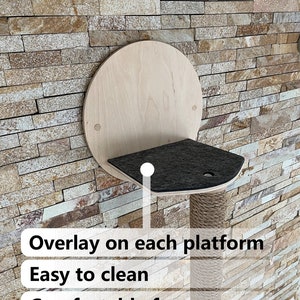 May include: A wall-mounted cat tree with a round wooden platform and a scratching post covered in sisal rope. The platform has a removable, black, felt overlay. The text "Overlay on each platform", "Easy to clean", and "Comfortable for cat" is visible below the cat tree.
