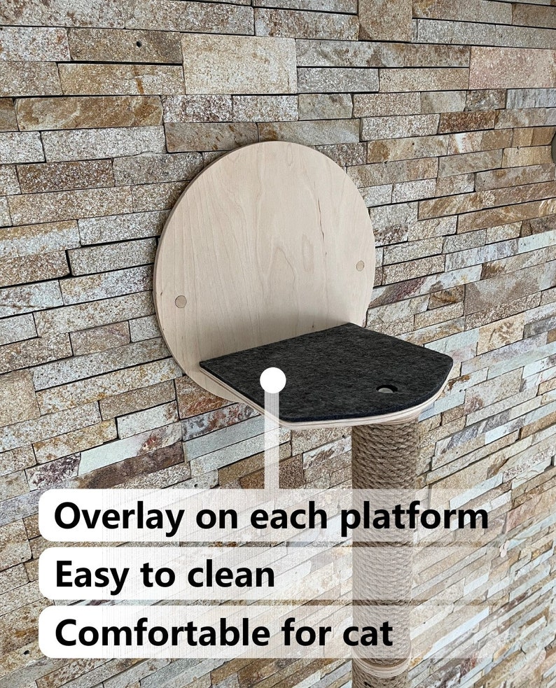 May include: A wall-mounted cat tree with a round wooden platform and a scratching post covered in sisal rope. The platform has a removable, black, felt overlay. The text "Overlay on each platform", "Easy to clean", and "Comfortable for cat" is visible below the cat tree.