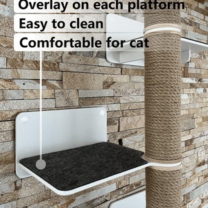 K&ouml;nnte beinhalten: Ein wei&szlig;er Katzenbaum mit einem Sisal-bekleideten Kratzbaum und mehreren Plattformen. Die Plattformen sind mit einem dunkelgrauen Stoff bezogen und haben den Text "Overlay on each platform", "Easy to clean" und "Comfortable for cat" aufgedruckt.