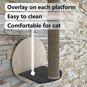 May include: A wall-mounted cat scratching post with a round platform and a sisal rope covered post. The platform is covered in a dark gray fabric. The text "Overlay on each platform", "Easy to clean", and "Comfortable for cat" is visible on the image.