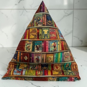May include: A triangular fabric stand featuring a colorful print of various vintage book spines on shelves. The pattern includes detailed illustrations of classic literary titles and characters, creating a stacked library effect across the entire surface.